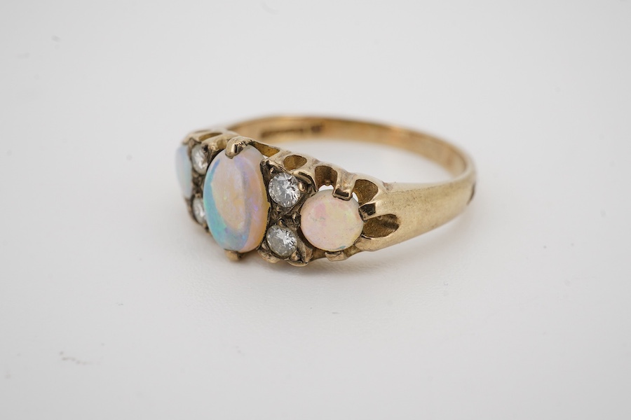 A modern 9ct gold, three stone white opal and four stone diamond set half hoop ring, size N, gross weight 2.4 grams.